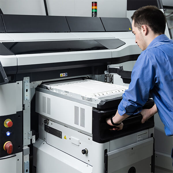 A Sole Dynamix technician working at a high-end 3D printer that is creating custom insoles.