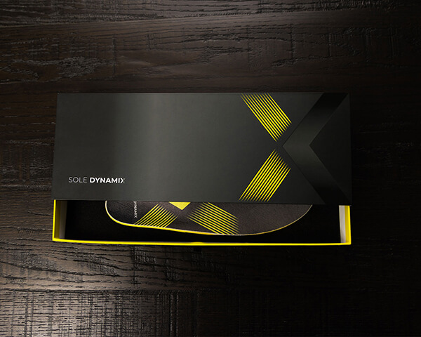 Sport-style shoe insoles in a partly opened Sole Dynamix box on a table.